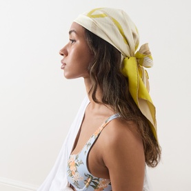 Model with Loewe Silk Printed Square Scarf in beige and yellow, tied as a headscarf, worn with a floral bikini top