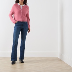 Model wearing Marc O Polo Berry Rose wool cardigan with white shirt, styled with dark blue flared jeans and black heeled boots.