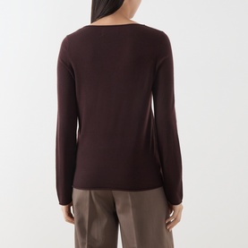 Model wearing Marc O Polo Black Cherry wool knit top, shown from behind, with long sleeves and a scoop back neckline, styled with taupe trousers.