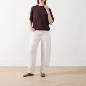 Model wearing Marc O Polo Black Cherry short-sleeve T-shirt with white wide-leg jeans and taupe loafers