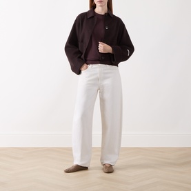 Model wearing Marc O Polo Black Cherry T-shirt, styled with dark cropped jacket, white wide-leg trousers and taupe flat shoes.