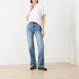 Model wearing Marc O Polo white cotton T-shirt, styled with light blue flared jeans, brown belt and brown loafers.