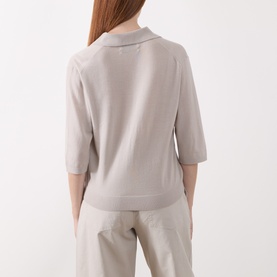 Model wearing Marc O Polo natural wool-blend top, rear view, showing short sleeves, open collar, and ribbed hem with tailored trousers.