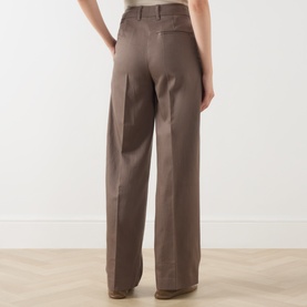 Model wearing Marc O Polo Stone Taupe wide-leg trousers, rear view showing back pockets and relaxed fit on light wood floor