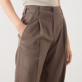 Model wearing Marc O Polo Stone Taupe wide-leg trousers with front pleats, button waistband, and side pocket. Styled with a cream top.
