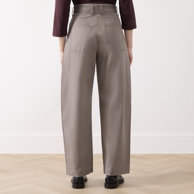 Model wearing Marc O Polo Stone Taupe wide-leg trousers, rear view, styled with a dark burgundy top and black shoes.