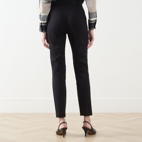 Model wearing Max Mara Studio black slim-leg trousers, rear view, styled with a checked jacket and black heeled mules.