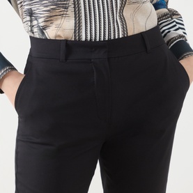 Model wearing Max Mara Studio black cotton-elastane trousers with slim fit, belt loops and side pockets, styled with a printed top.