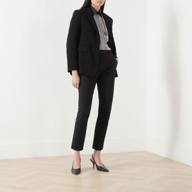 Model wearing Max Mara Studio black cotton-blend slim-leg trousers, styled with a black blazer, striped shirt, and black slingback heels.