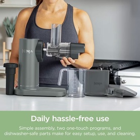 Ninja slow juicer in grey with detached components shown, including jug and cleaning brush, on kitchen countertop