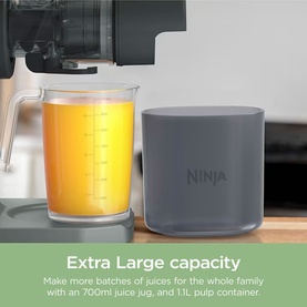 Ninja juicer with 700ml glass juice jug filled with orange juice and grey 1.1L pulp container on wooden surface.