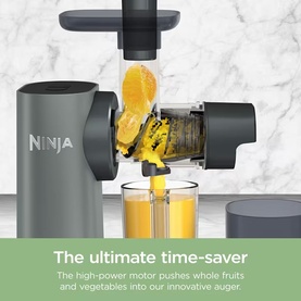 Ninja cold press juicer in grey, shown in action with orange being pressed through auger into clear collection cup