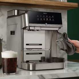 Ninja AutoBarista Pro Coffee Machine in stainless steel, styled on marble countertop with iced coffee glass and cloth beside it