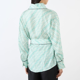 Model wearing Victoria Beckham Alba Silk Printed Wrap Blouse in blue with all-over logo print, contrast piping trim and self-tie belt, rear view.