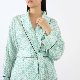 Model wearing Victoria Beckham Alba Silk Printed Wrap Blouse in blue with geometric print, shawl collar, contrast piping, and wrap front