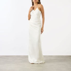 Model wearing Victoria Beckham ivory satin maxi dress with V-neckline, ruched bodice, and strappy cross-back detail.