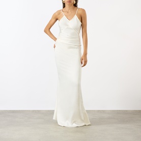 Model wearing Victoria Beckham ivory satin slip maxi dress with V-neckline, ruched waist, and cross-back straps.