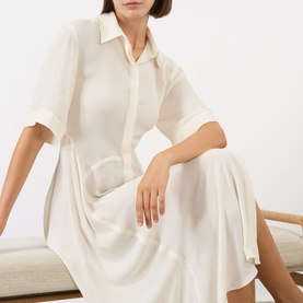 Model wearing Victoria Beckham Panelled Shirt Dress in white, featuring shirt collar, dropped shoulders, short sleeves and flared midi skirt