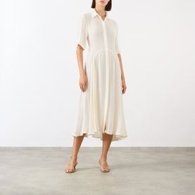 Model wearing Victoria Beckham Panelled Shirt Dress in white, with shirt collar, short sleeves, dropped waist and flared midi skirt. Styled with