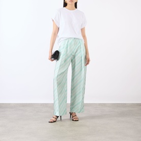 Model wearing Victoria Beckham blue wide-leg trousers with geometric print, styled with white tee, black strappy heels and small clutch bag.