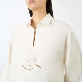 Model wearing Victoria Beckham white top with half-zip neckline and contrast brown embroidered detail at chest