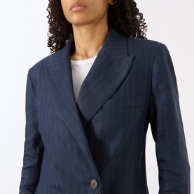 Model wearing Anine Bing navy pinstripe wool blazer, featuring notched lapels and single-button fastening, styled with a white top.