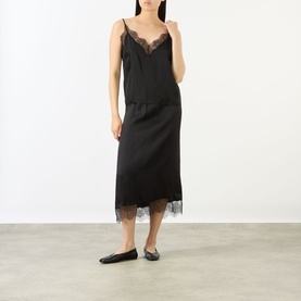 Model wearing Anine Bing Mael Lace-Trim Cami in black satin with V-neck and lace trim, styled with a matching black lace-hem skirt and flat shoes.