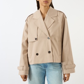 Model wearing Anine Bing beige cropped double-breasted trench coat with wide cuffs and notched lapel, styled with light blue jeans