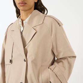 Model wearing Anine Bing beige cotton trench coat, close-up showing notched lapel, double-breasted buttons and epaulette detail