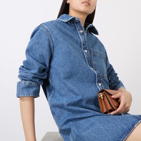 Model wearing Anine Bing blue denim shirt dress in 100% cotton, styled with a small brown handbag with gold hardware.