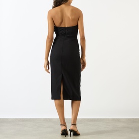 Model wearing Anine Bing black strapless midi dress with ruched bodice, back split and black strappy heels.