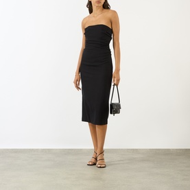 Model wearing Anine Bing black strapeless ruched midi dress, styled with strappy sandals and carrying a small black mini bag.