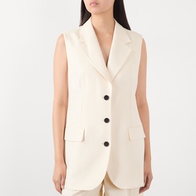 Model wearing Anine Bing cream gilet with notched lapel, single-breasted black button fastening and welt pockets.