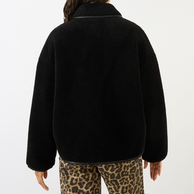 Model wearing Anine Bing black teddy fleece jacket, back view, styled with leopard print trousers.