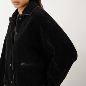 Model wearing Anine Bing black textured fleece jacket with leather-trim collar and patch pockets, button-front fastening.