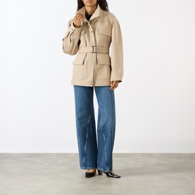 Model wearing Anine Bing Odin Utility Jacket in beige with stand collar, belted waist and flap pockets, styled with wide-leg jeans and black flats.
