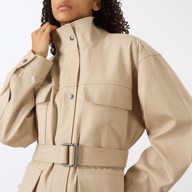 Model wearing Anine Bing Odin Utility Jacket in beige, featuring stand collar, snap button placket and buckle belt waist detail.