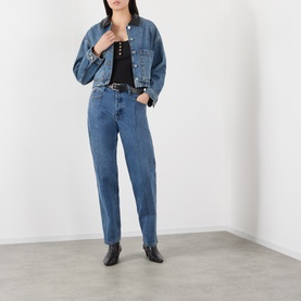 Model wearing Anine Bing washed blue denim jacket, styled with matching blue jeans, black top, and black ankle boots.