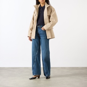 Model wearing Anine Bing Brie Twisted Seam Jeans in Cabana Blue, wide-leg high-rise fit, styled with beige jacket and black heels.