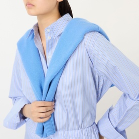 Model wearing Anine Bing Essie Striped Shirt in Washed Blue cotton, styled with a light blue jumper tied at shoulders.