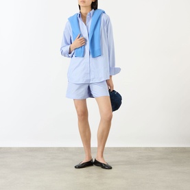 Model wearing Anine Bing Essie Striped Shirt in Washed Blue with matching shorts, styled with a blue knit vest, navy bag and black flats.