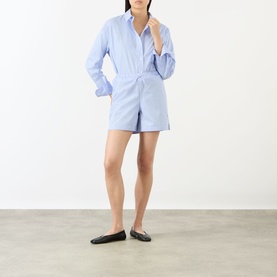 Model wearing Anine Bing Ramy Striped Shorts in Washed Blue with matching striped shirt and black flat mules.