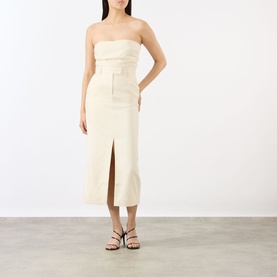 Model wearing Anine Bing cream midi skirt with front split, styled with matching strapless top and black strappy sandals.
