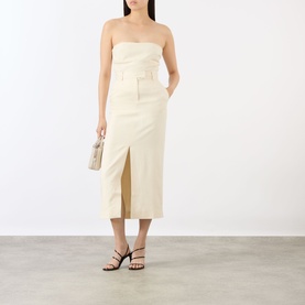 Model wearing Anine Bing cream midi skirt with front slit, styled with matching strapless top and black strappy heels.