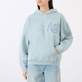 Model wearing Anine Bing Harvey Logo Drawstring Hoodie in blue with AB chest logo, styled with light wash jeans.