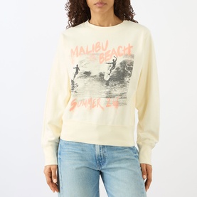 Model wearing Anine Bing Sweat Top in Washed Buttercream with Malibu Beach surf graphic print, styled with light blue jeans.