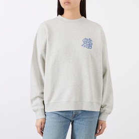 Model wearing Anine Bing grey cotton sweatshirt with blue graphic chest print, styled with light blue jeans