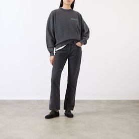 Model wearing Anine Bing black cotton sweat top with small chest logo, styled with black straight-leg jeans and black loafers.