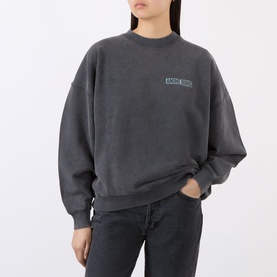 Model wearing Anine Bing black cotton sweatshirt with small chest logo graphic, styled with dark wash jeans