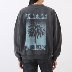 Model wearing Anine Bing black cotton sweatshirt with Malibu Beach palm tree graphic on back, styled with dark jeans.